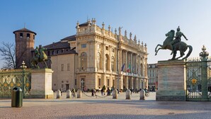 A historic building with classical architecture, a statue of a man on horseback, and a prominent tower. - Torino Centro | Bertola House (Turin)