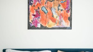 A room with a blue headboard, a colorful abstract painting on the wall, and a white pillow on the bed. - Torino Centro | Bertola House (Turin)