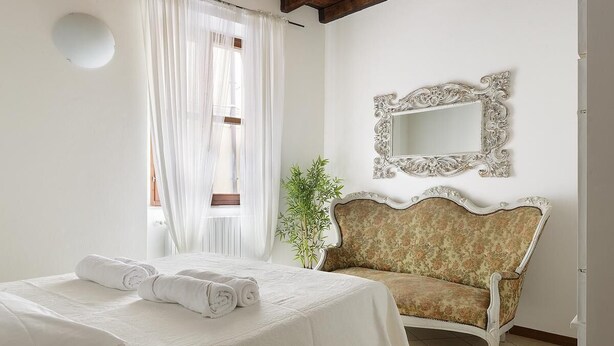 Ein Hotelzimmer mit Bett, Sofa, Spiegel und einer Pflanze.
