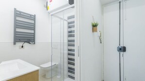 Une salle de bain moderne avec un lavabo blanc, des toilettes et une douche à parois de verre.