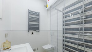 Une salle de bain moderne avec un lavabo blanc, une douche en verre et un porte-serviettes.