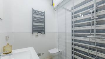 Ein modernes Badezimmer mit einem weißen Waschbecken, einer Glasdusche und einem Handtuchhalter.