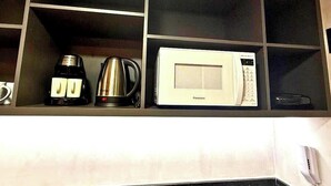 A kitchen with a microwave, coffee maker, and kettle on a shelf. - LM GET SENSE PE NA AREIA (Joao Pessoa)