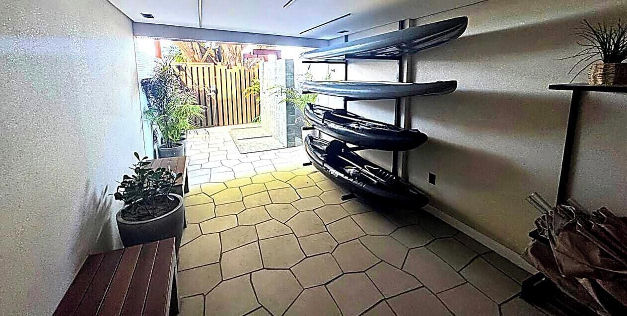 Kapea käytävä, jossa on laatoitettu lattia, penkki ja seinälle kiinnitetty hylly.