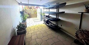 Ein schmaler Korridor mit Fliesenboden, einer Bank und einem an der Wand befestigten Ablagefach.