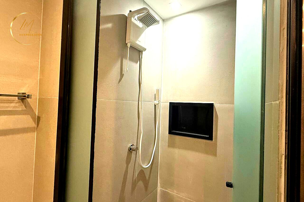 Une douche équipée d’un pommeau de douche à main et d’un panneau de commande fixé au mur.