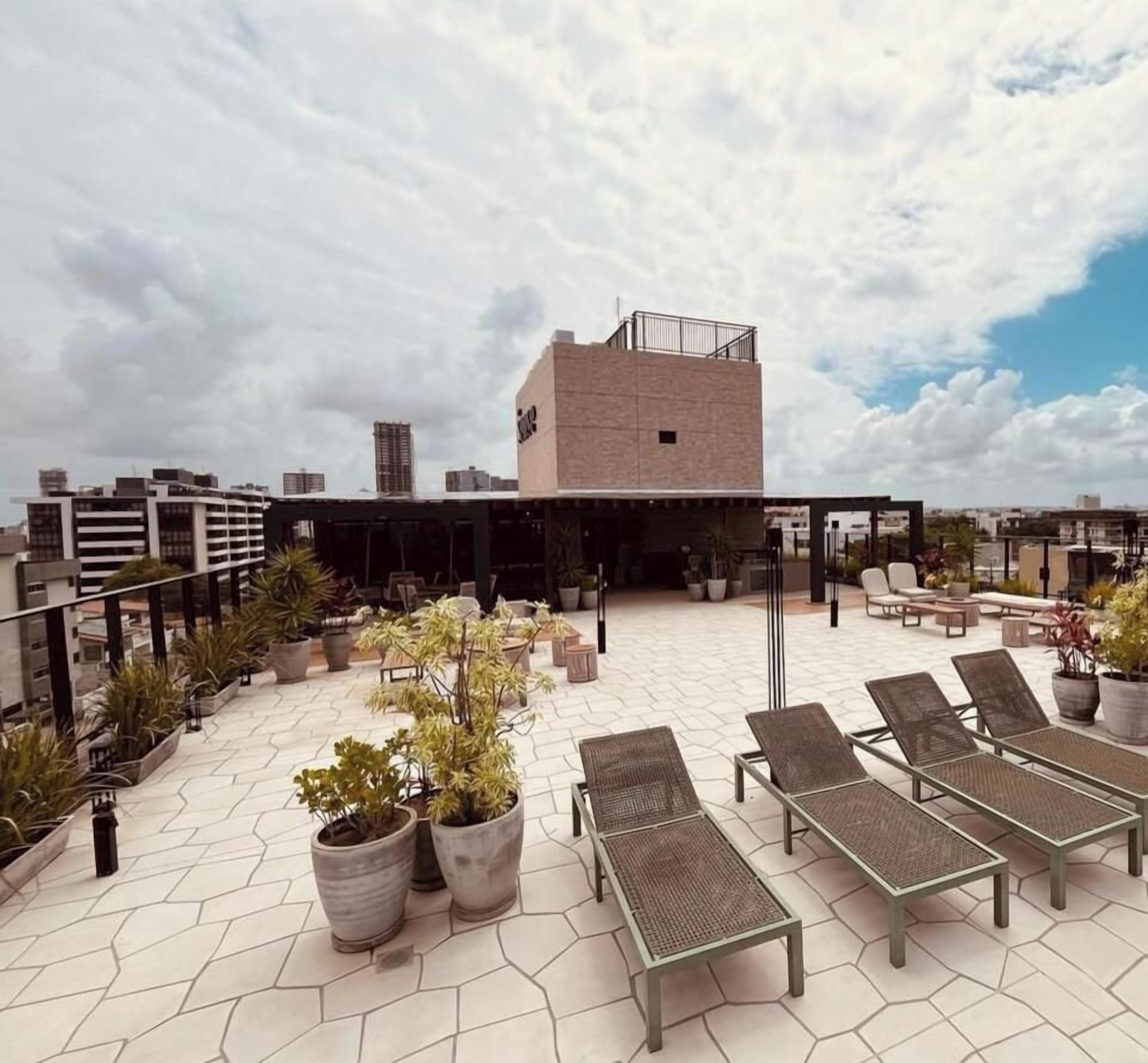 En tagterrasse med liggestole, krukkeplanter og udsigt over bybilledet.