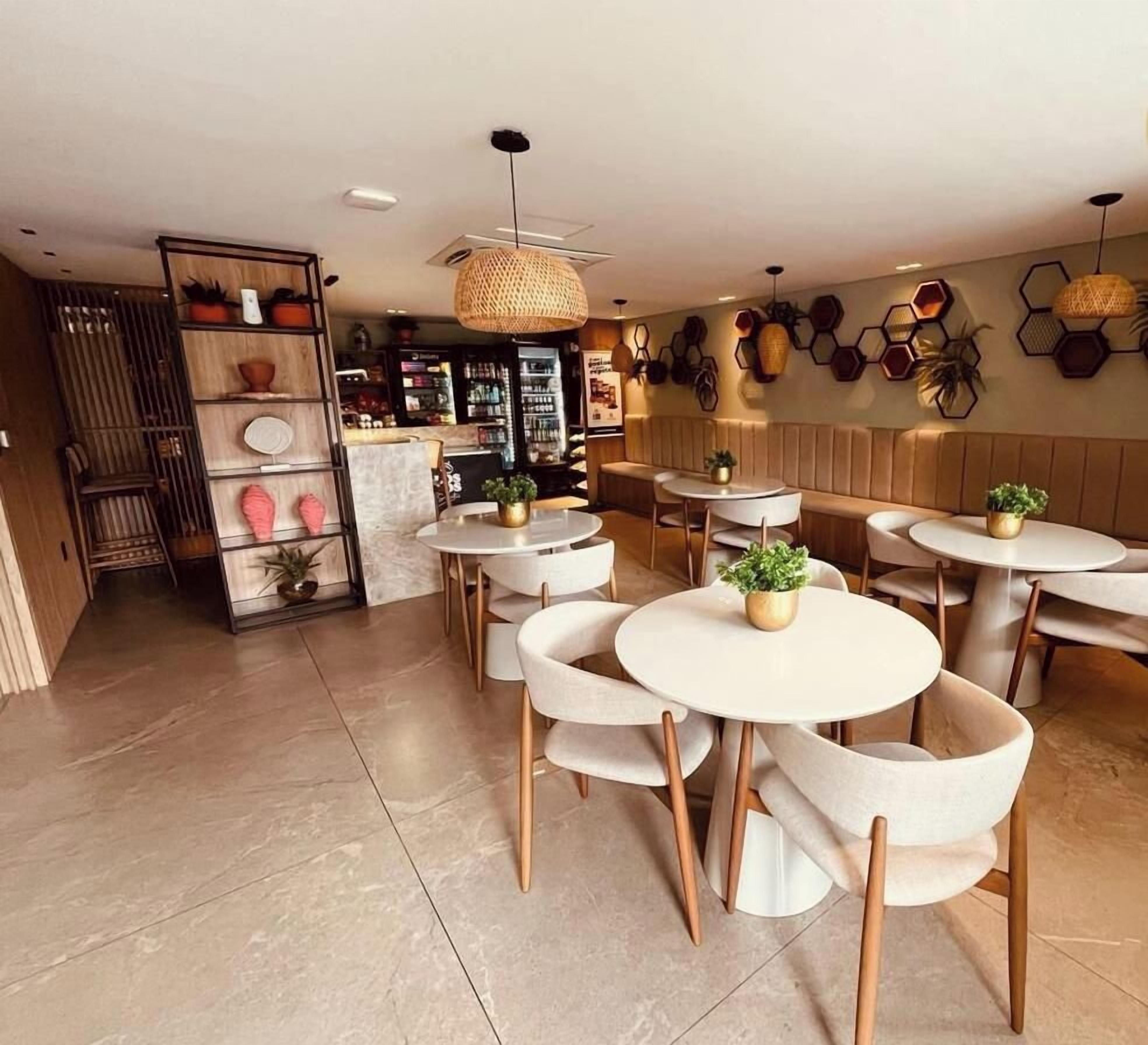 A cafe interior with round tables, chairs, and a variety of potted plants.