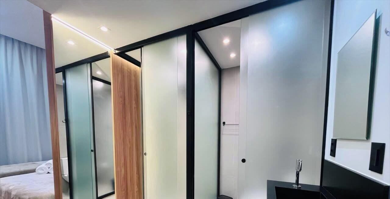 A modern hotel room with a bed, a wardrobe, a mirror, and a small table.