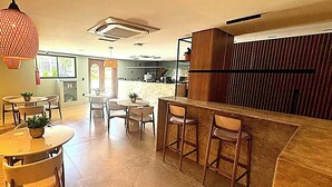 A modern interior with a bar area, seating arrangements, and a kitchen in the background. - LM GET SENSE PE NA AREIA (Joao Pessoa)