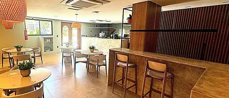 A modern interior with a bar area, seating arrangements, and a kitchen in the background.