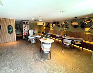 Ein Restaurantinneres mit runden Tischen, Stühlen, einer Holzwand und einer Wand mit sechseckartigen Verzierungen.