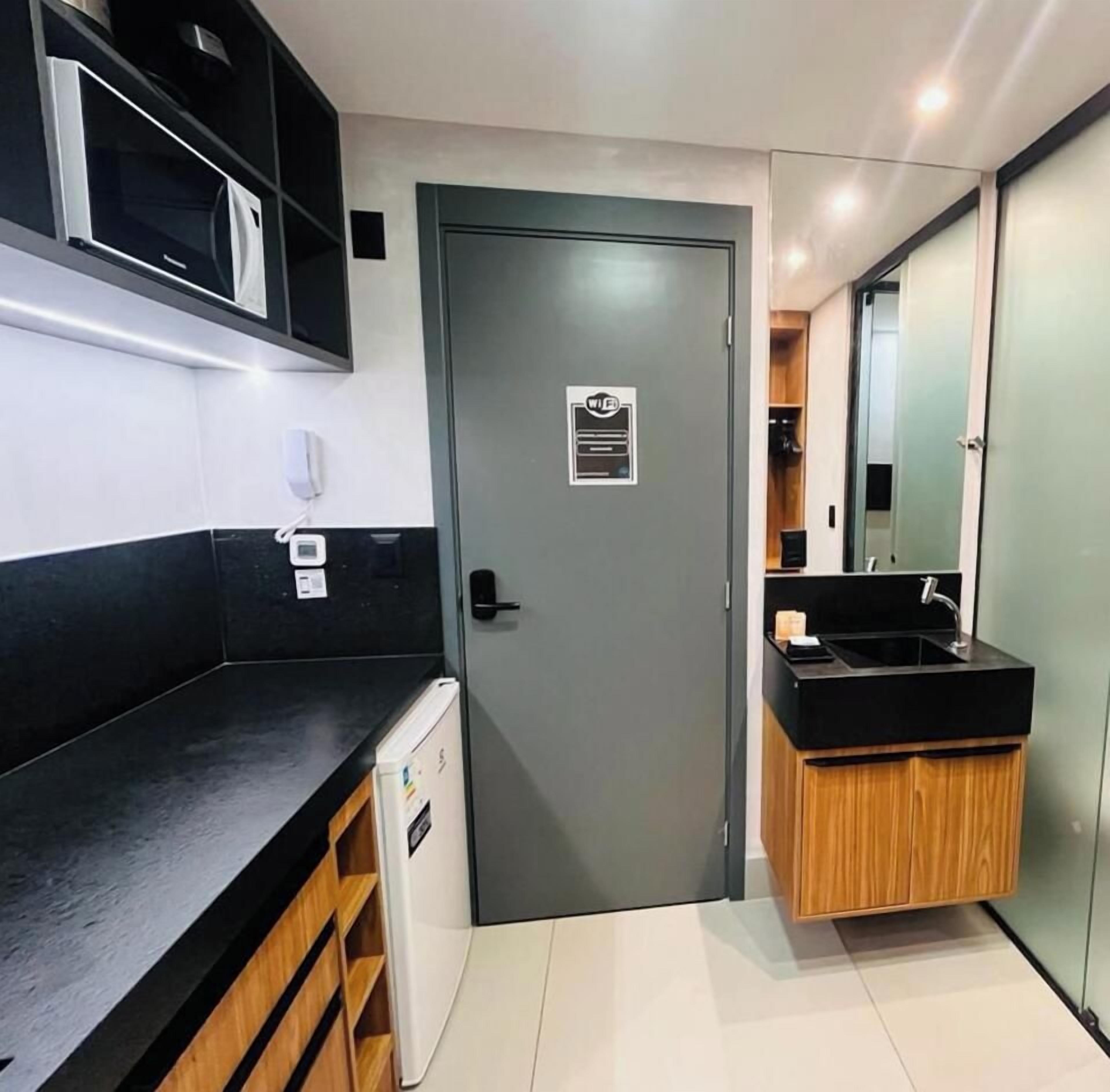 A compact kitchen with a microwave, a refrigerator, a sink, and a cabinet.