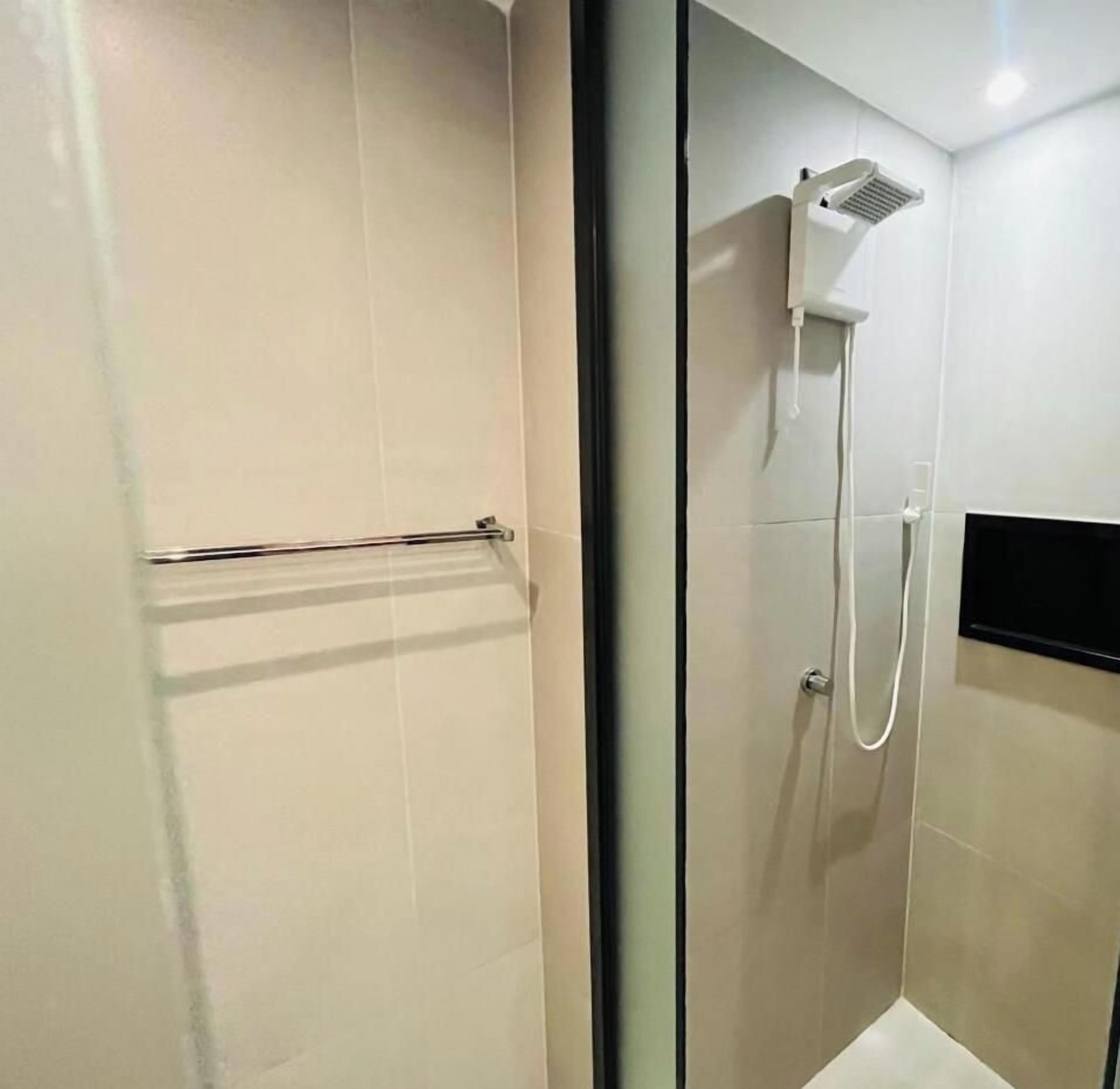Un baño moderno con cabina de ducha de vidrio, un perchero y un panel de control en la pared.