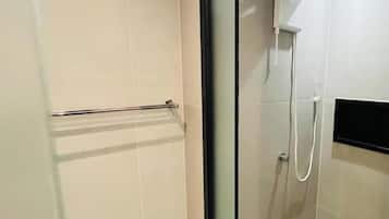 Un baño moderno con cabina de ducha de vidrio, un perchero y un panel de control en la pared.