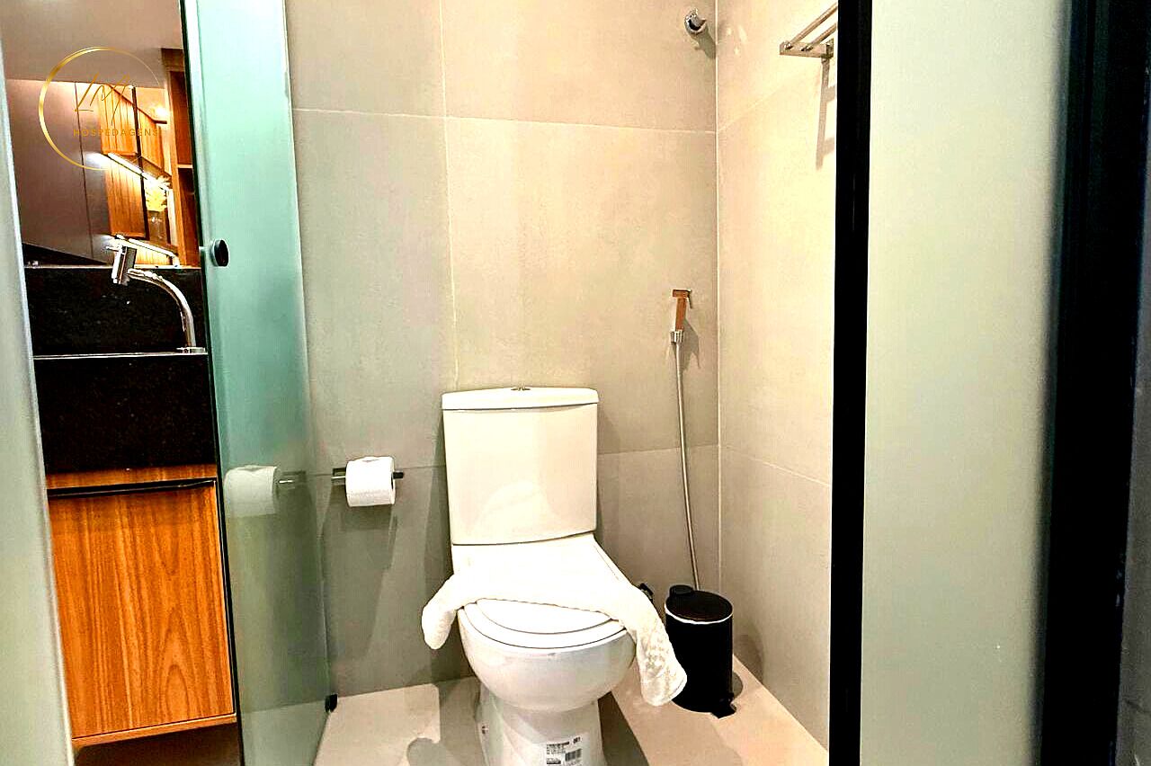 Un baño con inodoro, bidé y cubo de basura.