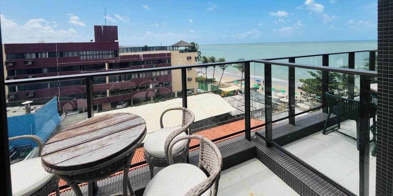 Un balcón con vista a la playa y edificios de hotel.
