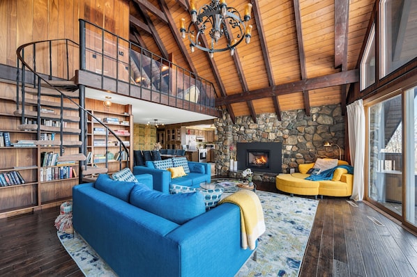 A spacious living room with a blue sofa, a yellow armchair, and a stone fireplace.