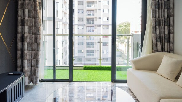 A modern living room with a glass coffee table, a beige sofa, and a view of a residential building through large windows. - Welcome to Summerville homes ,the cozy haven nestled in the heart of Nairobi. (Nairobi)