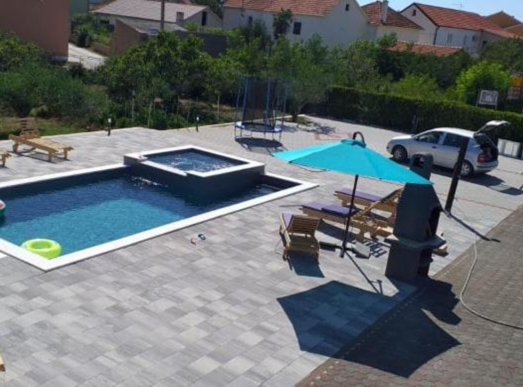 Een zwembad met een jacuzzi, ligbedden en een barbecue.