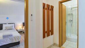 Hotellihuone, jossa on sänky, yöpöytä ja suihkutila.