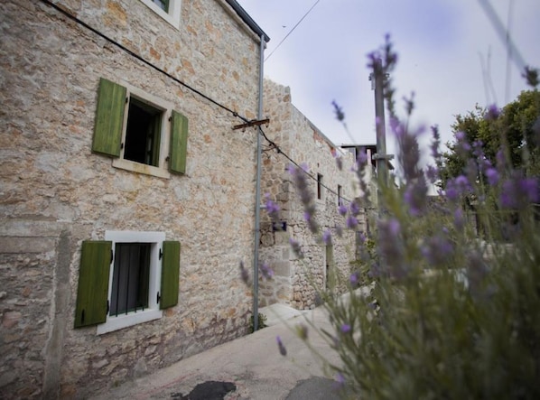 A stone building with two windows, each with green shutters.