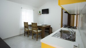 A compact kitchen with a dining area, a built-in stove, and a small shelf with a plant.