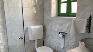 Un baño moderno con inodoro, dispensador de toallas de papel y barra para toallas.