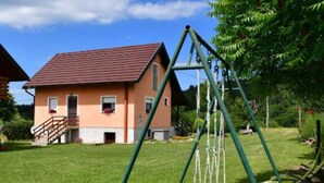 Una casa amb teulada vermella, un porxo i un parc infantil al pati.