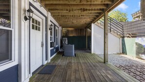Un porche abrité avec un plancher en bois, une porte blanche et une fenêtre.