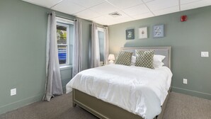 Une chambre à coucher avec un lit, des rideaux, une fenêtre et des œuvres d’art murales.