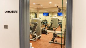 Et fitnessrum med træningsudstyr, fjernsyn og spejl.