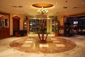 A lobby with a central round table, a chandelier, and a checkered floor pattern. - Majestic Central Hotel (Dubai)