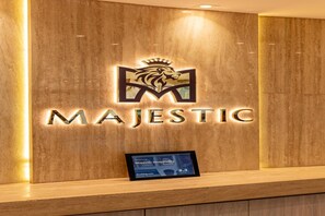 A wooden reception desk with the 'MAJESTIC' logo and a digital display. - Majestic Central Hotel (Dubai)