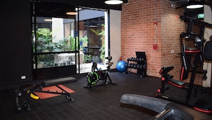 A gym with exercise equipment, a large window, and a brick wall.