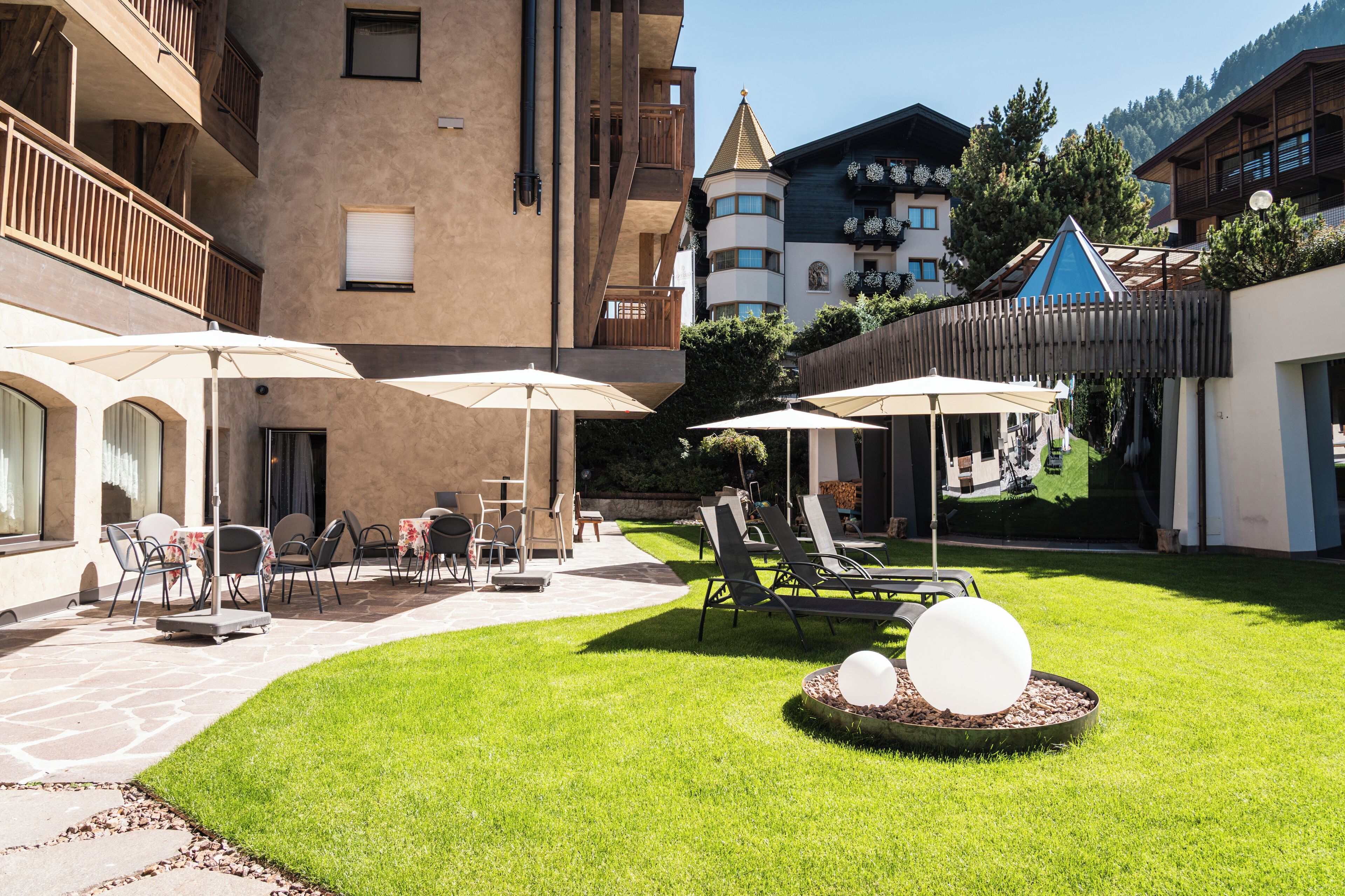 Un patio con mesas al aire libre, sombrillas y una estructura esférica decorativa.