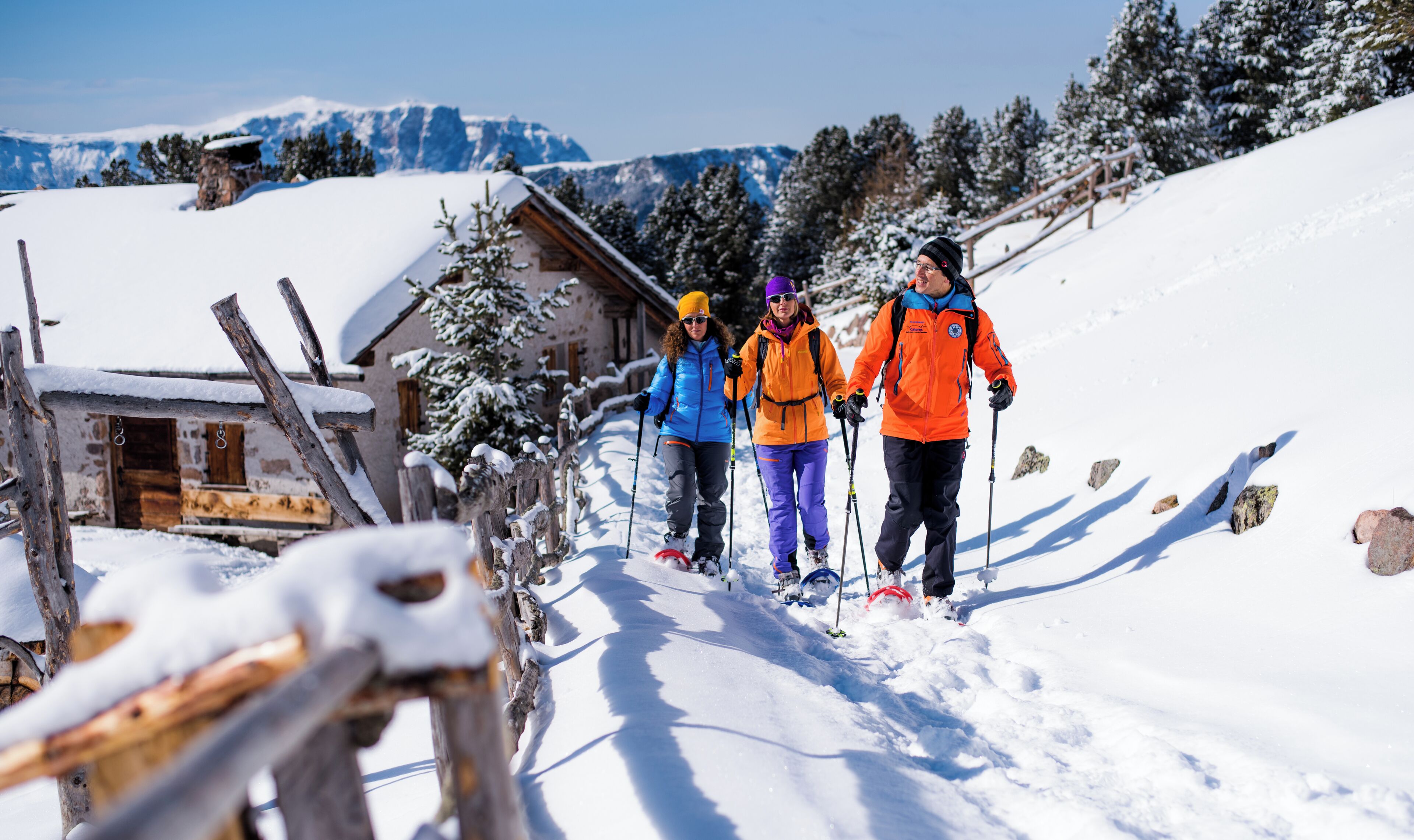 A wooden cabin with snow-covered surroundings, a clear sky, and distant mountains.