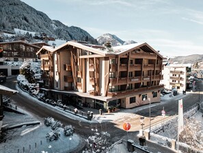 A multi-story hotel with a modern architectural design, featuring balconies and a ski resort backdrop. - Hotel COSMEA Dolomites (Castelrotto)