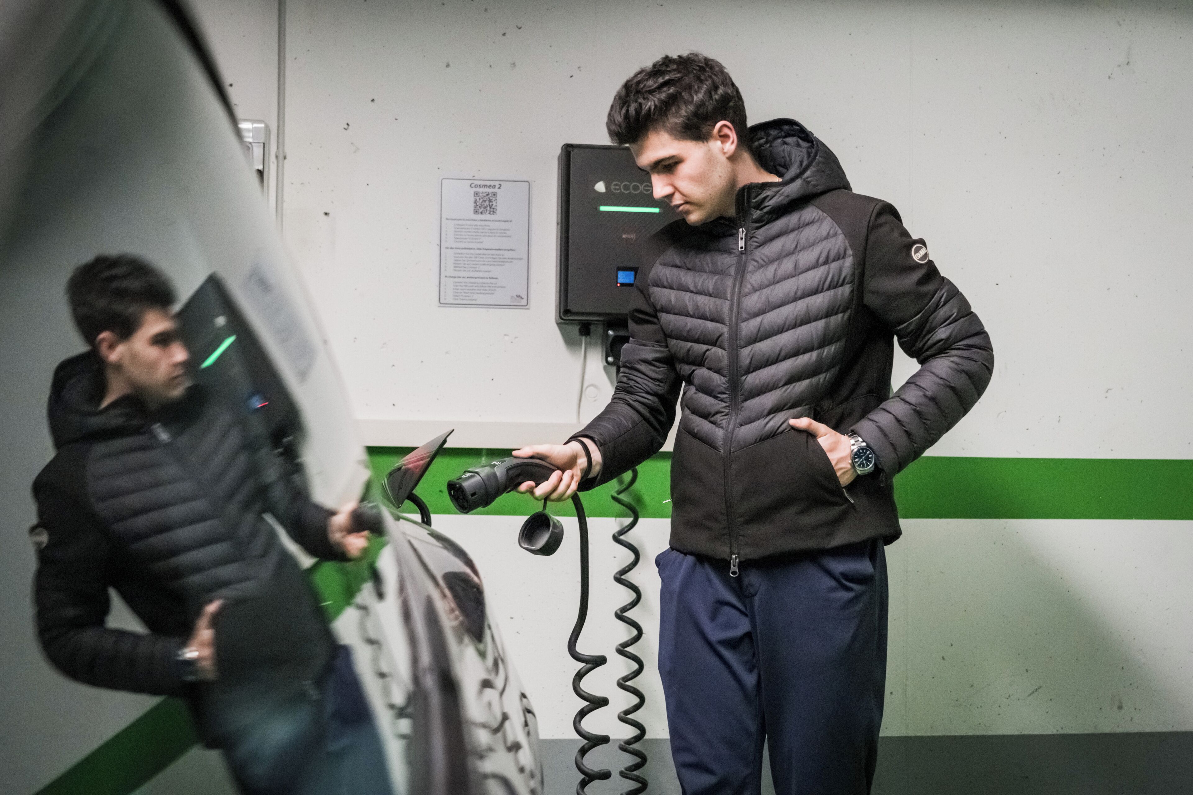 Une personne utilisant un appareil de recharge sur un véhicule.