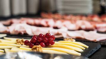 Een charcuteriebord met verschillende vleessoorten, kaas en fruit.