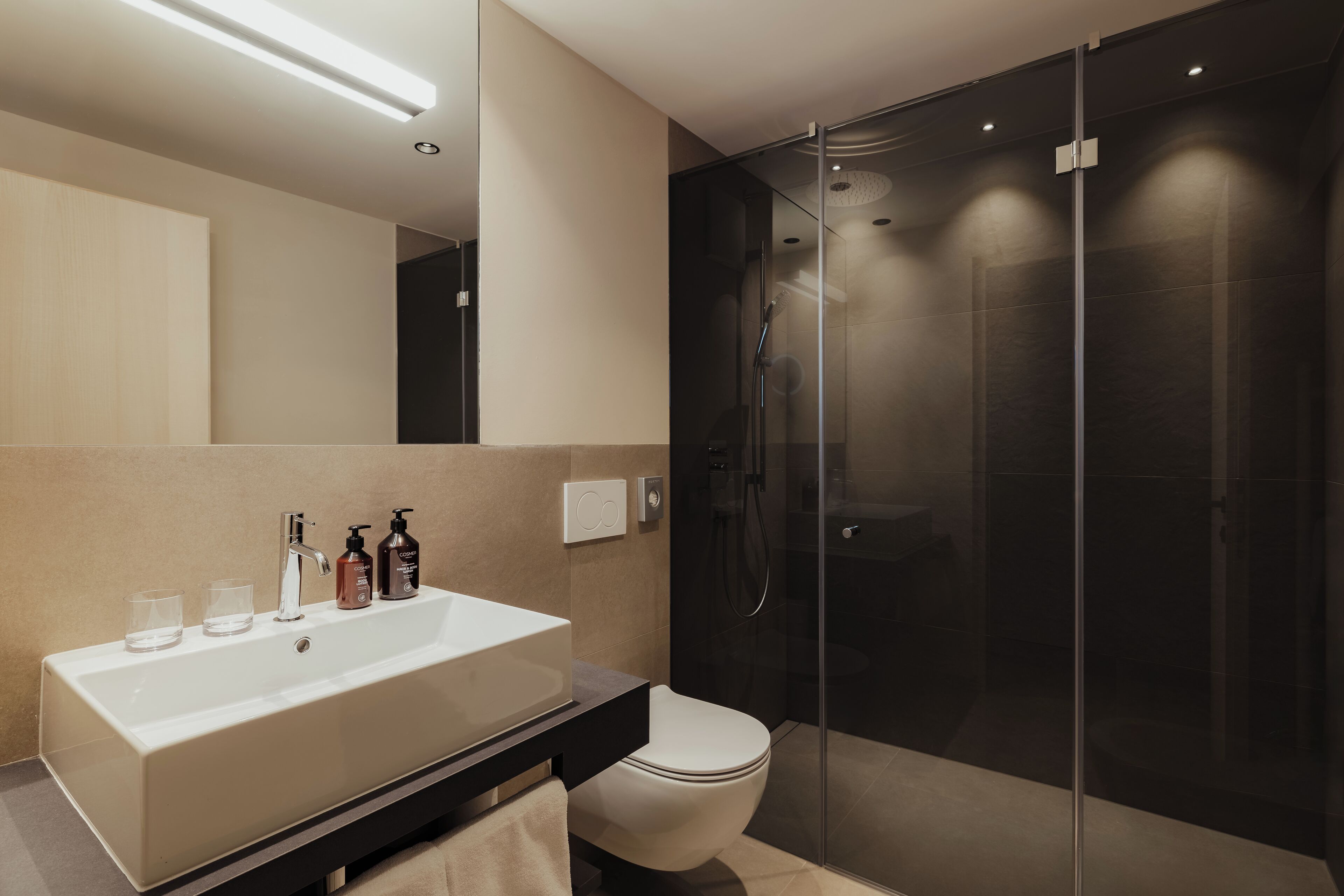 Un baño moderno con un lavamanos grande, espejo y cabina de ducha de vidrio.