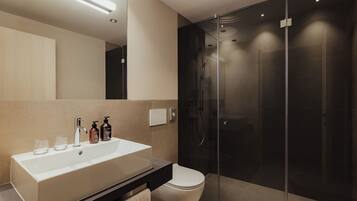 Un baño moderno con un lavamanos grande, espejo y cabina de ducha de vidrio.