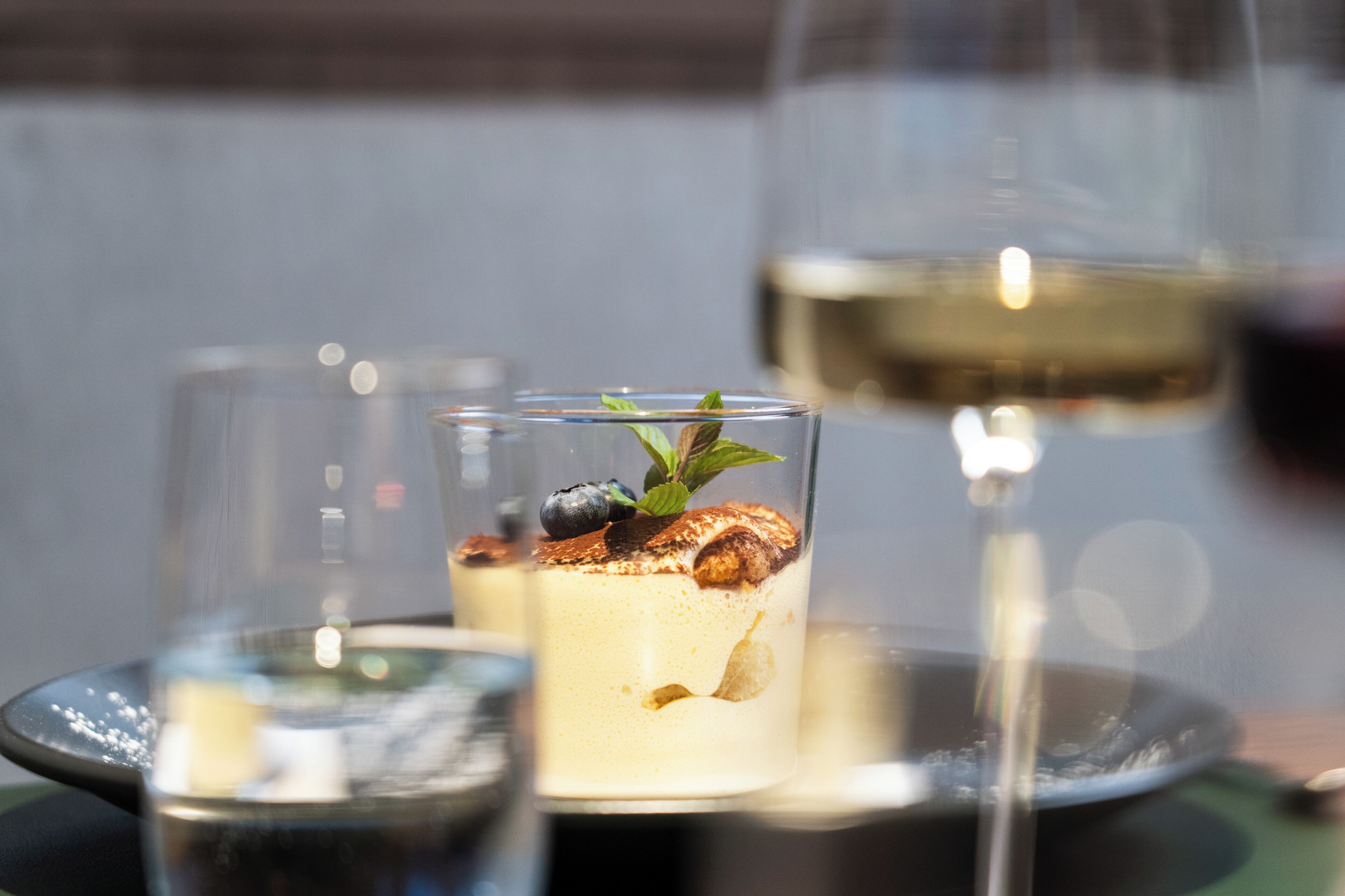 Un dessert à la poire et aux myrtilles, présenté dans un verre transparent.