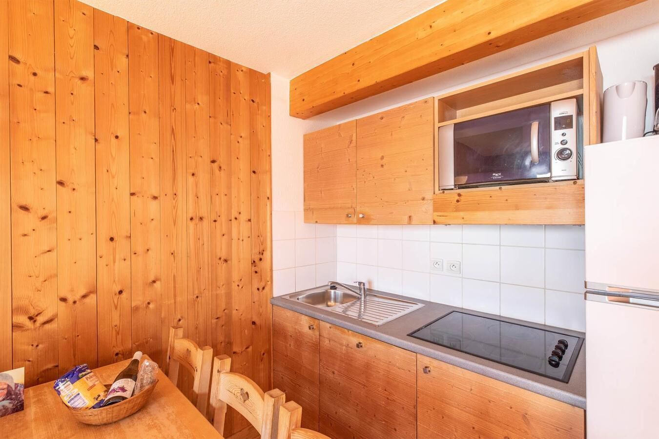 A kitchen with wooden cabinets, a microwave, a sink, and a stove.