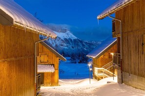 A wooden cabin with a snow-covered roof and a staircase leading to a second level.