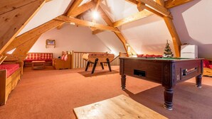 A cozy attic room with a wooden beam ceiling, a pool table, a sofa, and a small Christmas tree. - Wifi, 100m from ski slopes, swimming pool, sauna, terrace, balcony, parking, tv, ski locker, 56m² (Les Déserts)