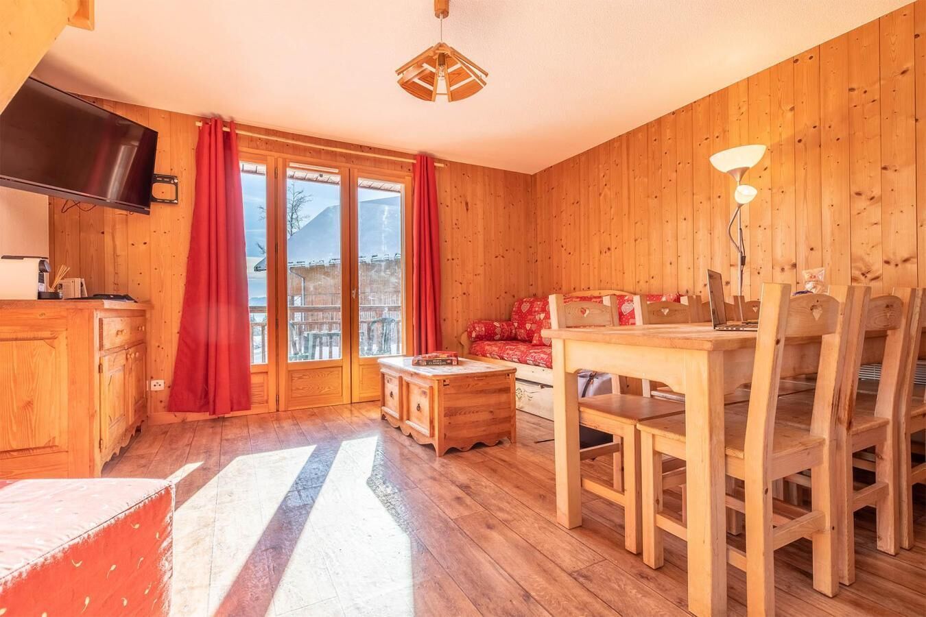 Un intérieur en bois comprenant une table à manger, des chaises, un canapé et un téléviseur.