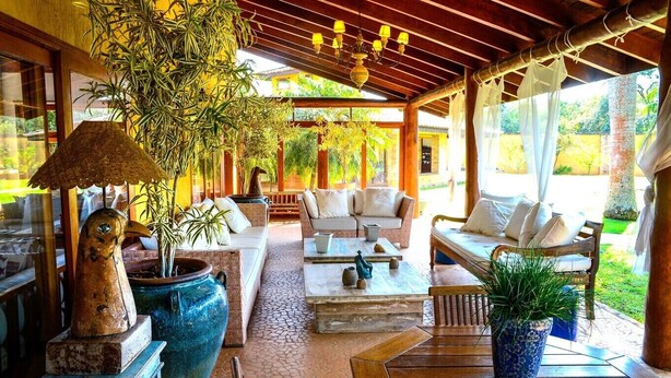 Un espacio al aire libre cubierto con sofás, una mesa de centro y plantas en macetas.