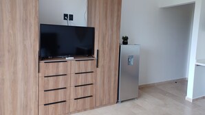 A modern kitchen with a built-in wooden cabinet, a flat-screen TV, and a stainless steel refrigerator. - Studio in Centro Maya area of Playa Del Carmen-full kitchen, AC, smart TV, pool. (Playa del Carmen)