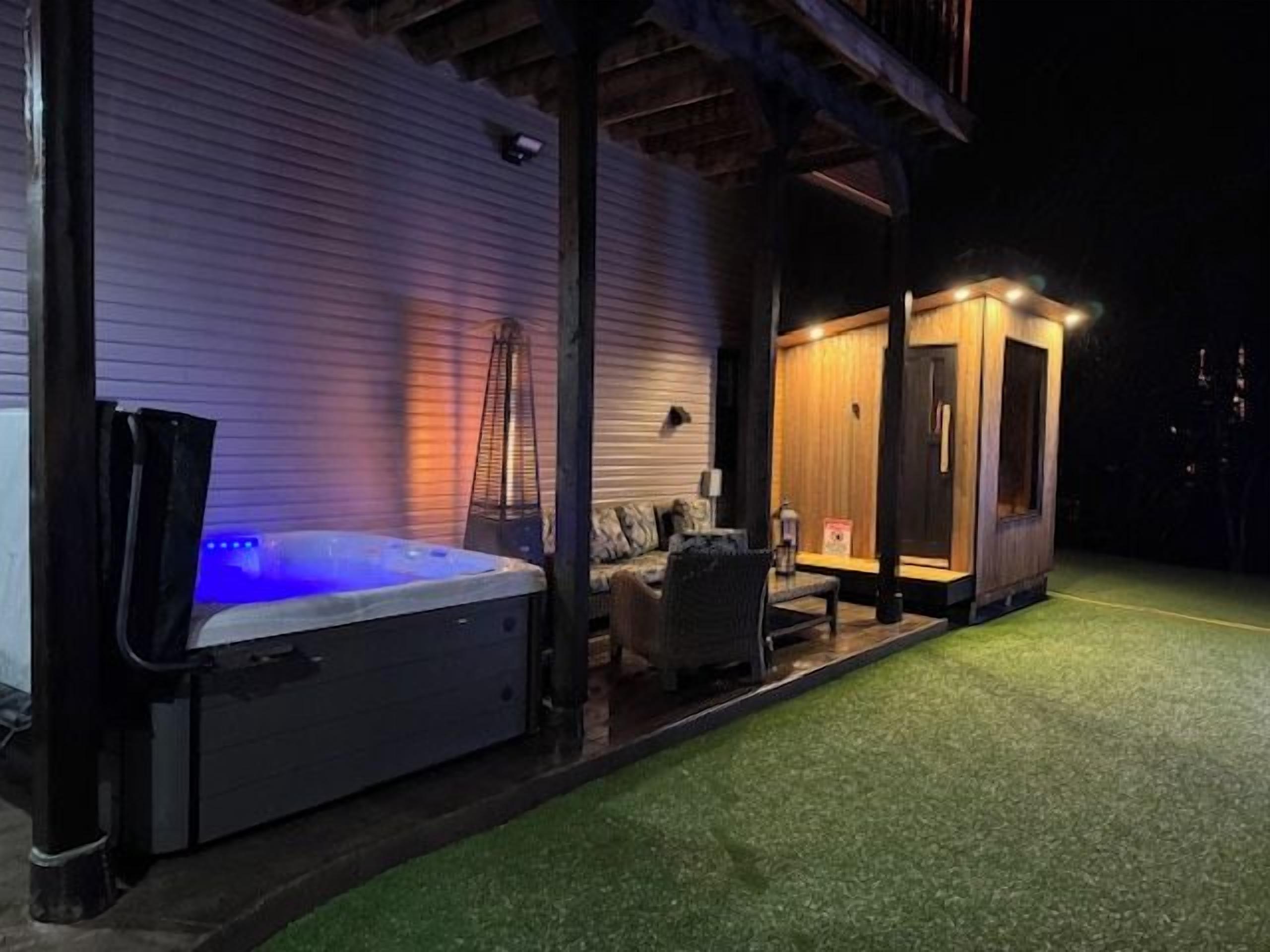 Een hottub buiten een gebouw, met een overdekte zithoek en een klein houten bouwwerk.